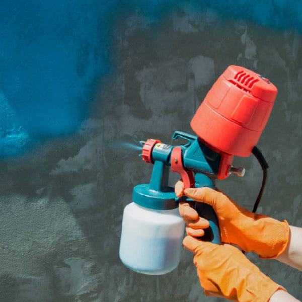 Hands covered with orange gloves using an orange paint sprayer