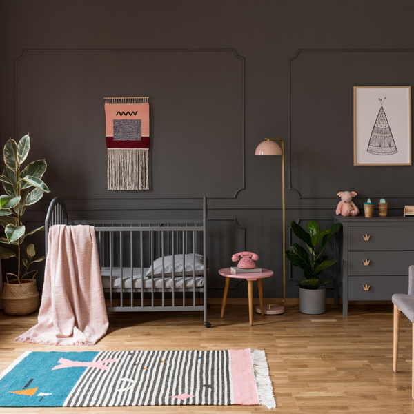 A unique nursery color palette with darker walls and pops of pink throughout the space 