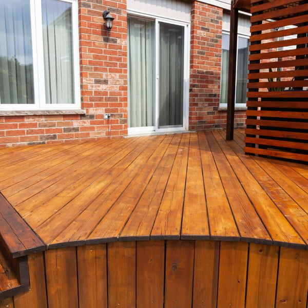 Back of a brick house with a wooden deck freshly coated in brown stain at Hoover Paint near Murfreesboro, TN
