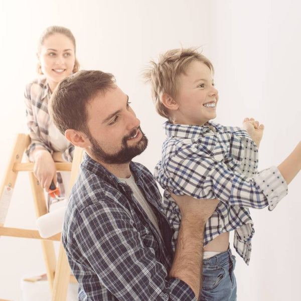 Father lifting son while he uses water-based paint to paint walls green as mom looks on at Hoover Paint near Nashville, TN