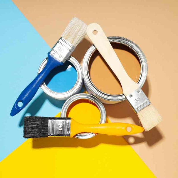 Colorful background with three open paint cans and three paintbrushes arranged in a triangle at Hoover Paint near Central Tennessee